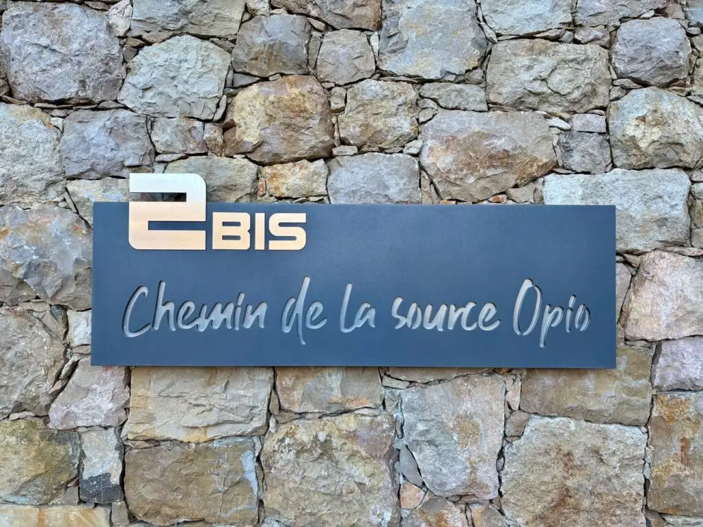 plaque sur un mur en pierre d'entrée de batiment thermolaquée aluminium et peinture bleu