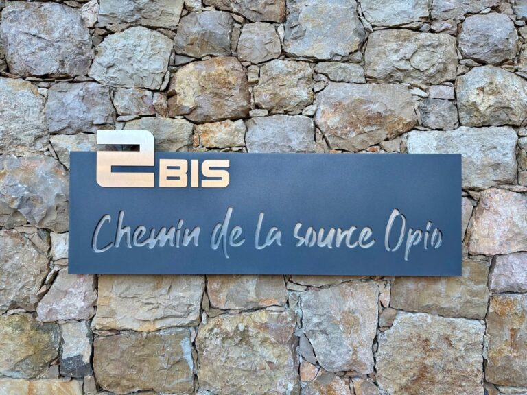 plaque sur un mur en pierre d'entrée de batiment thermolaquée aluminium et peinture bleu